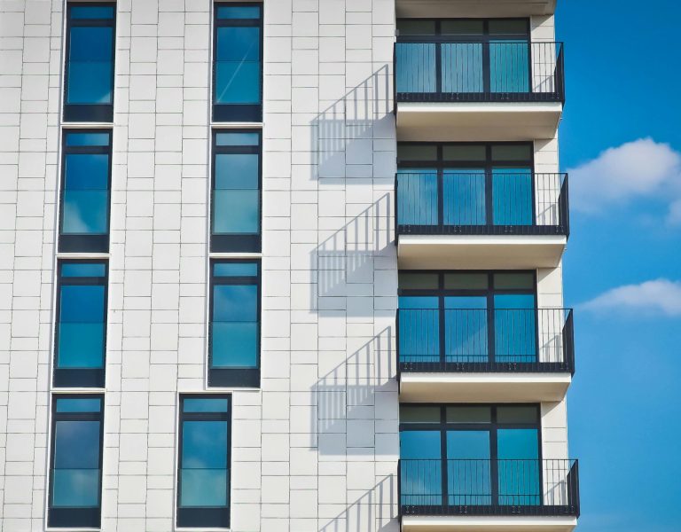 Contemporary urban apartment building with framed glass windows against clear blue sky.